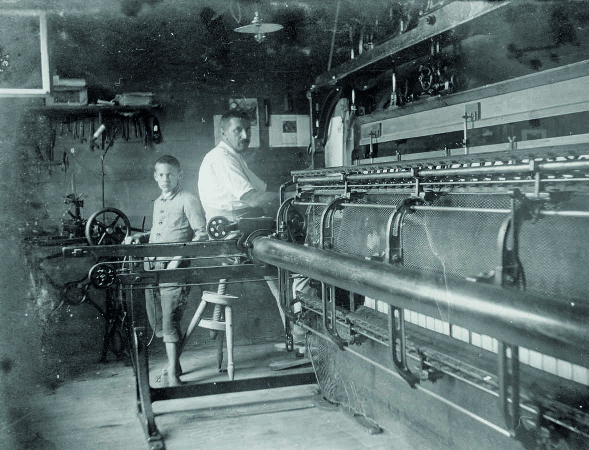 Heimsticker am Pantograph (verkleinert Vorlage und reproduziert sie mehrfach) der Handstickmaschine, Knabe an Fädelmaschine, um 1912, wohl Appenzell  © Schweizerisches Nationalmuseum 