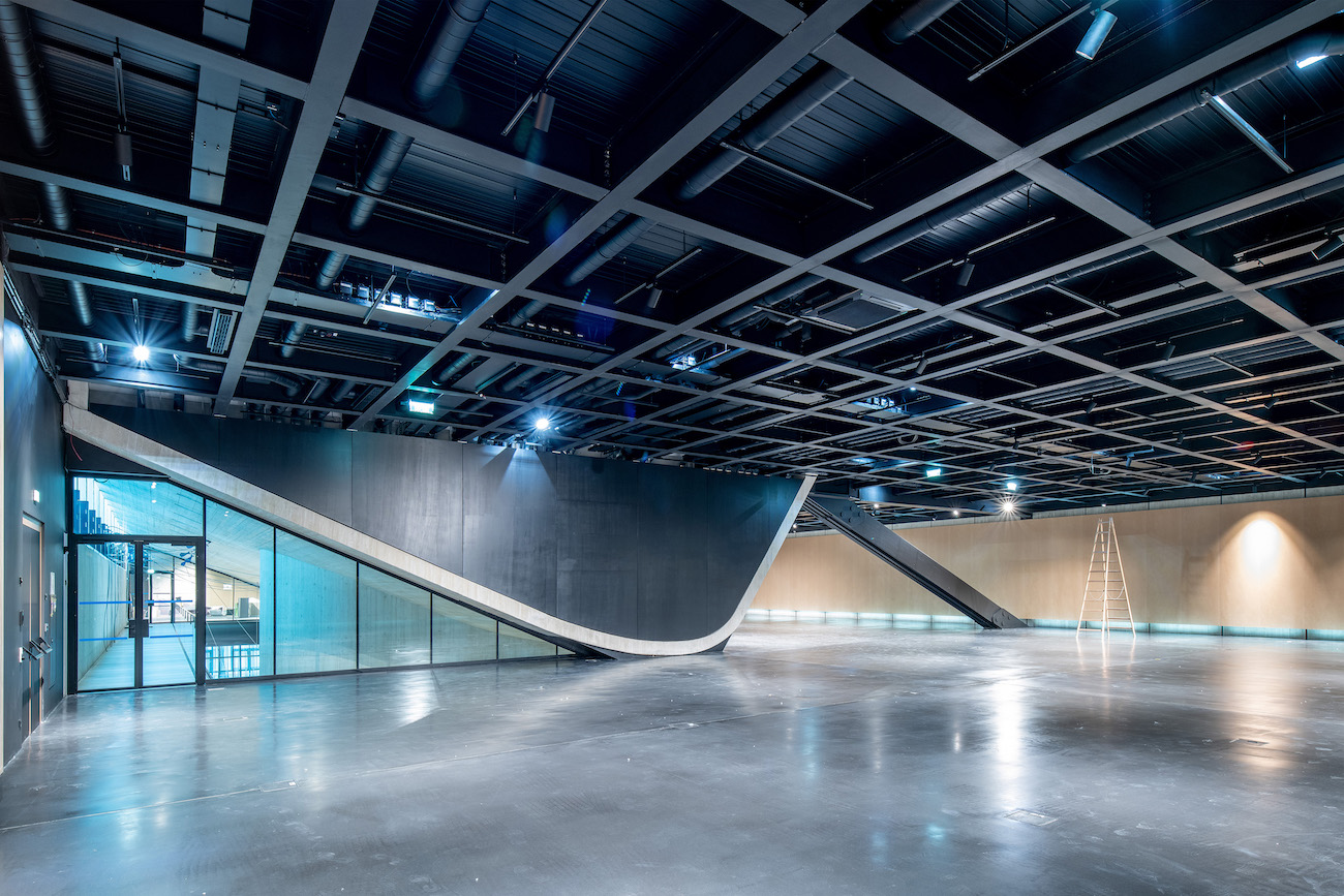 Im introvertierten Kubus des Ausstellungsgeschoßes bleiben die Stahlbänder sowie die geschwungene Decke des Atriums sichtbar. (© Kollektiv Fischka)